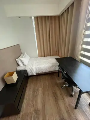 a room with a bed and a desk and a table at Makati City Serenity Tower 2501 in Manila