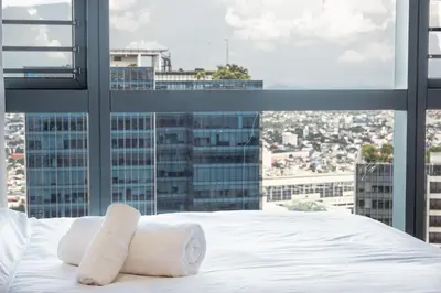 a bedroom with a white bed and a large window at Premium 2 Bedroom and 1 Living Room Suite with Balcony - One Uptown, BGC in Manila