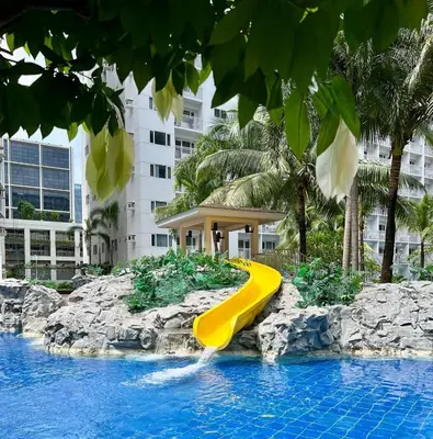 a yellow slide in a pool at a resort at Casa JYD at Shore Residences - Mall of Asia in Manila