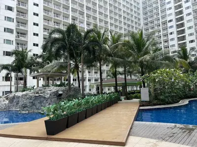 a resort with a pool and palm trees and a building at Casa JYD at Shore Residences - Mall of Asia in Manila