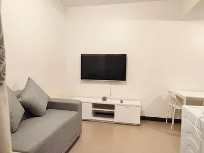 a living room with a couch and a tv on a wall at The Intramuros Suite in Manila