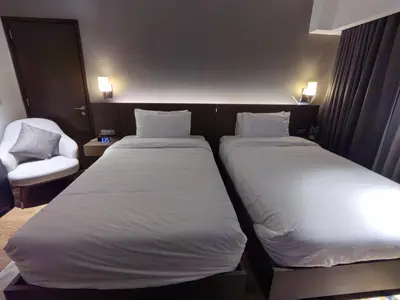 two beds in a hotel room with a chair at Acqua Private Residences in Manila