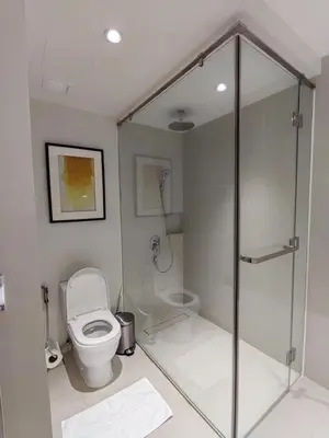 a bathroom with a toilet and a glass shower stall at Acqua Private Residences in Manila
