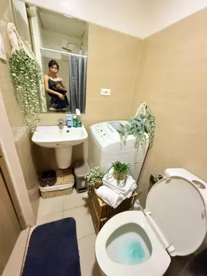 a woman taking a picture of a bathroom with a toilet and sink at Near NAIA AIRPORT in Manila