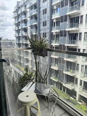 a balcony with a table and a stool and a building at LDN II Palm Tree Villa NAIA 3 in Manila