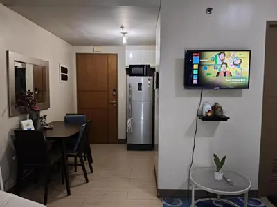 a living room with a refrigerator and a table with chairs at LDN II Palm Tree Villa NAIA 3 in Manila