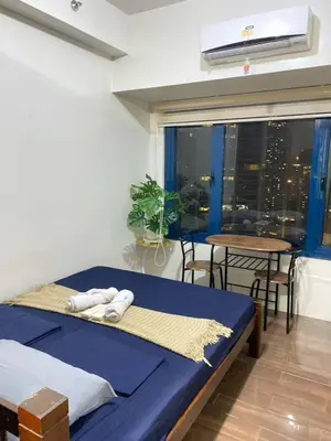 a bedroom with a bed and a table and a window at Air Residences in Manila