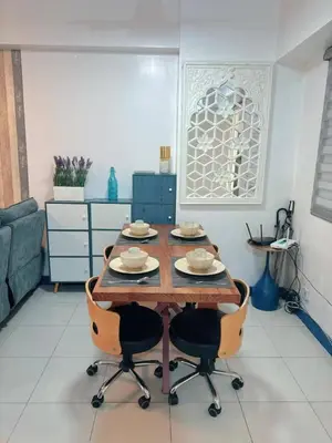 a wooden table in a living room with chairs at Torre De Manila in Manila