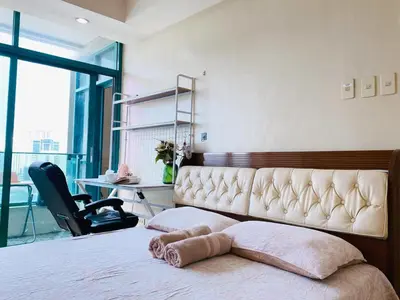 a bedroom with a bed with a chair and a desk at Seaview in Malate in Manila
