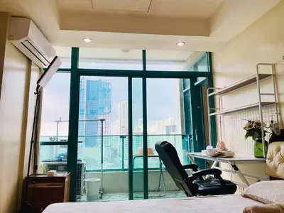 a bedroom with a bed and a desk and a window at Seaview in Malate in Manila