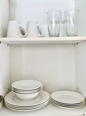 a kitchen with plates and glasses on shelves at Budget City View w Pool Access in BGC Taguig City in Manila