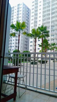 a table and a chair on a balcony with palm trees at Blytheo Urban Staycation by Jonathan in Manila