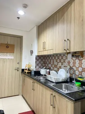 a kitchen with wooden cabinets and a sink at Blytheo Urban Staycation by Jonathan in Manila
