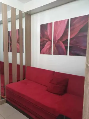 a red couch in a room with three paintings at Shore 2 tower 2 in Manila