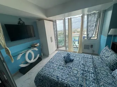 a bedroom with a cat laying on a bed with a television at Apple Paris Azure Staycation in Manila