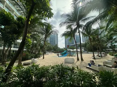 a sandy beach with palm trees and a playground at Apple Paris Azure Staycation in Manila