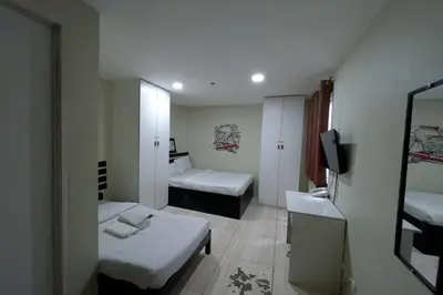 a small room with two beds and a television at Jardin Oriental Suites Ubelt Manila in Manila