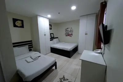 a small room with two beds and a television at Jardin Oriental Suites Ubelt Manila in Manila