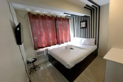 a small room with a bed with a red window at Jardin Oriental Suites Ubelt Manila in Manila