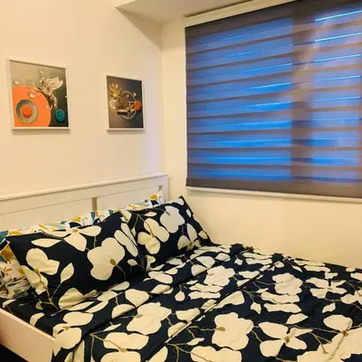a bedroom with a bed and a window with blue blinds at CGS Crib staycation in Manila