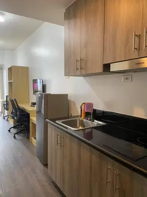 a kitchen with wooden cabinets and a sink and a desk at FX Property 3926 in Manila