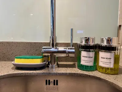 a sink with two bottles of soap and a mirror at Awesome Sunset View in Venice Mall Suite with PS5 30th edition, Walk to Everything, 5 mins away to BGC, DisneyPlus, Prime Video, HBO Max in Manila