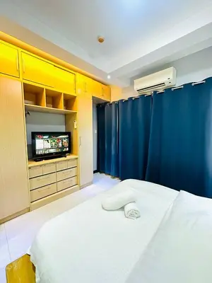 a bedroom with a bed and a tv and blue curtains at 1 Bedroom Seaview Room Korean Town heart of malate in Manila