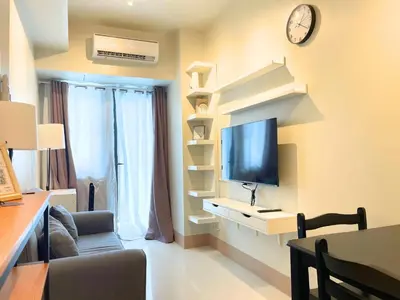 a living room with a tv and a couch and a clock at Shore Staycation at Shore 3 Mall of Asia in Manila