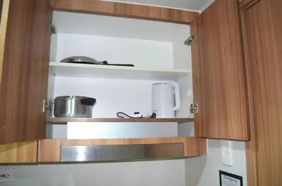 a kitchen with wooden cabinets with pots and pans at Shore Staycation at Shore 3 Mall of Asia in Manila