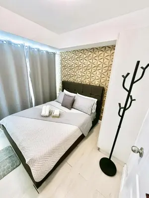a bedroom with a bed with white sheets and pillows at SM Bicutan Miami in Manila