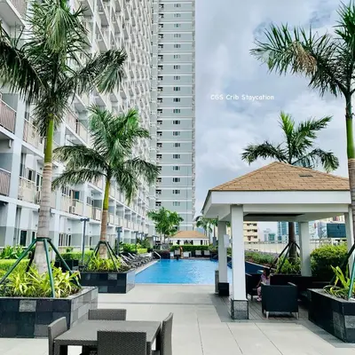 a hotel swimming pool with a gazebo and palm trees at CGS Crib staycation in Manila