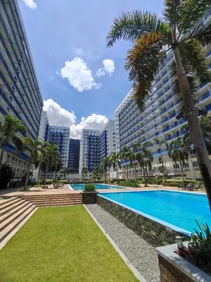 a swimming pool with palm trees and buildings at Staycationsite at Sea Residences in Manila