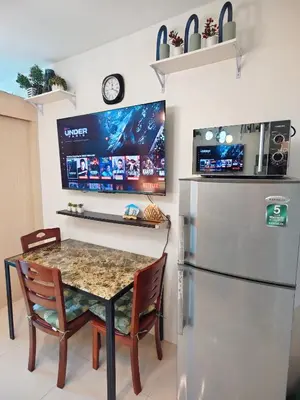 a kitchen with a table and a refrigerator at Staycationsite at Sea Residences in Manila