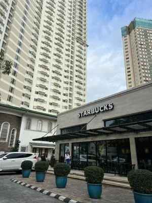 a starbucks restaurant in front of a large building at High and Cozy in Manila