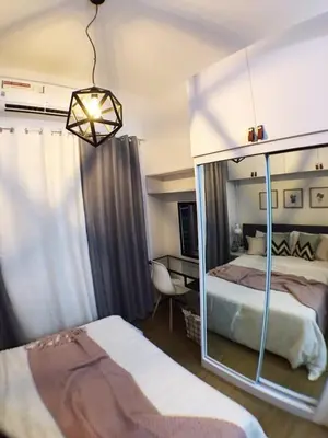 a bedroom with two beds and a chandelier at Airy condo w balcony, Netflix, 3 pools, sleeps 3 in Manila