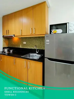 a kitchen with wooden cabinets and a stainless steel refrigerator at GV Holiday Homes - Shell Residences MOA - Cozy 1BR Apartment in Manila