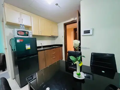 a small kitchen with a black refrigerator and a table at Studio Unit in One Palm Tree Villas across NAIA Terminal 3 in Manila