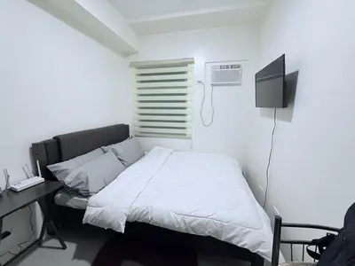 a bedroom with a bed and a desk and a tv at Urban Deca Towers Cubao in Manila