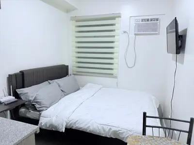 a bedroom with a bed and a window with a air conditioner at Urban Deca Towers Cubao in Manila