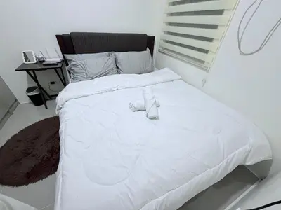 a white bed with white sheets and socks on it at Urban Deca Towers Cubao in Manila