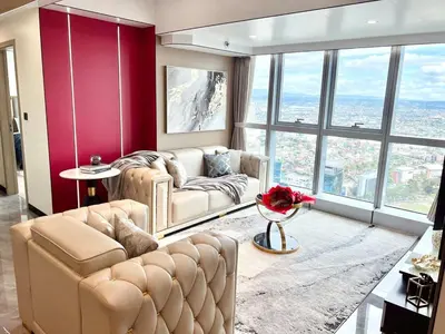 a living room with two chairs and a couch and windows at Executive 5BR Penthouse Suite in Uptown BGC in Manila
