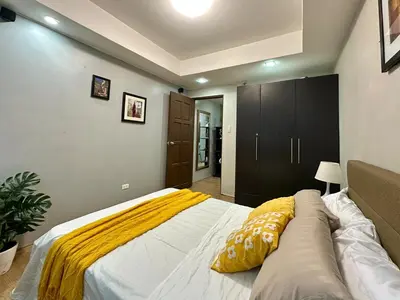 a bedroom with a large bed with yellow pillows on it at Spacious 1BR Condo with 300mbps WiFi in BGC in Manila