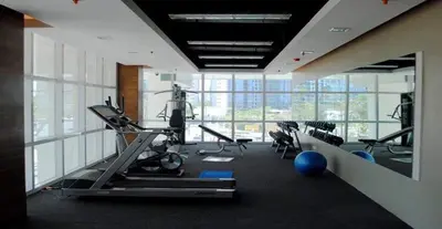 a gym with cardio equipment in a large room with windows at Spacious 1BR Condo with 300mbps WiFi in BGC in Manila