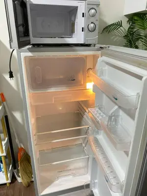 an open refrigerator with a microwave on top of it at Air Residences in Manila
