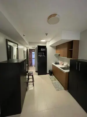 a kitchen with black cabinets and a black refrigerator at Makati City Antel Spa Residences 2306 in Manila