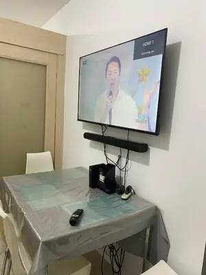 a flat screen tv hanging on a wall with a table at Janas Condotel in Manila