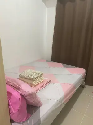 a bed with pink and white sheets and pillows on it at Janas Condotel in Manila