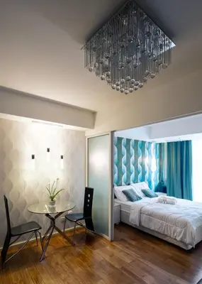 a bedroom with a bed and a table and a chandelier at SM Bicutan Condotels Felis in Manila