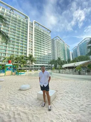 a man sitting on a bench on the beach in front of a building at SM Bicutan Condotels Felis in Manila