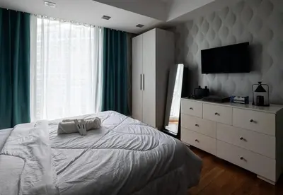 a bedroom with a bed and a dresser with a television at SM Bicutan Condotels Felis in Manila